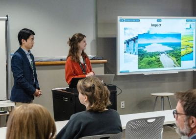 two students presenting in classroom with television
